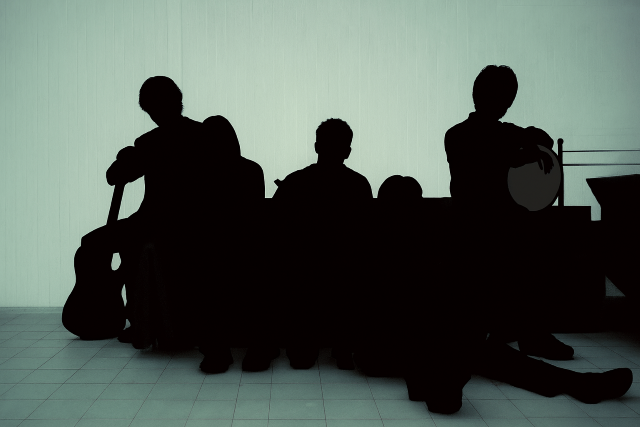 5人組の男性グループが楽器を持って並んでいるシルエット写真