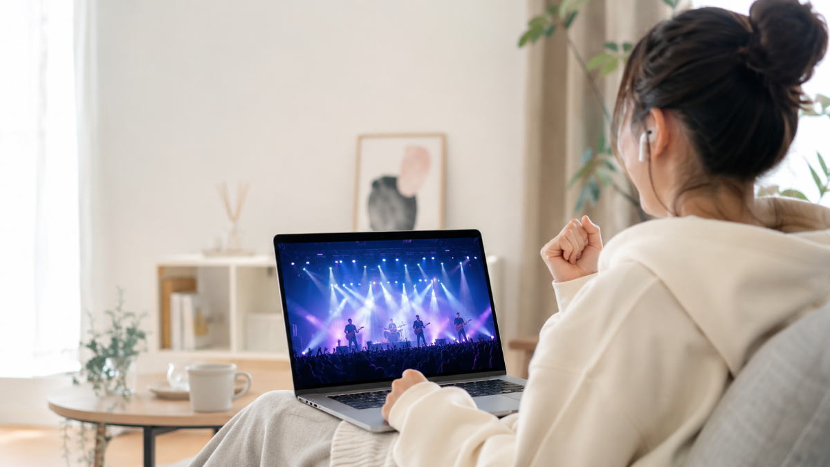 自宅のリビングでノートパソコンを使い、DISH//のライブ配信を楽しむ女性の後ろ姿